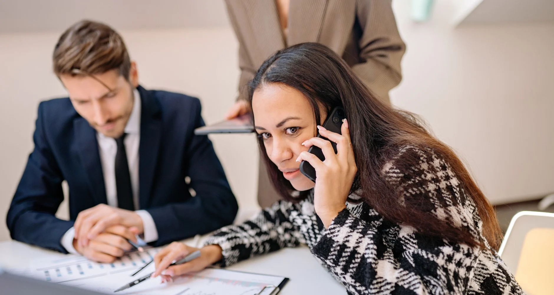 Two people reviewing paperwork during a phone call