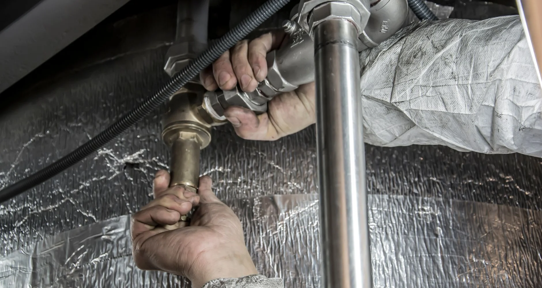 Plumber installing steel water pipes indoors