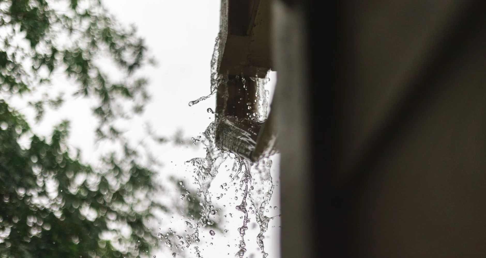 Rainwater pouring from a roof gutter during a storm