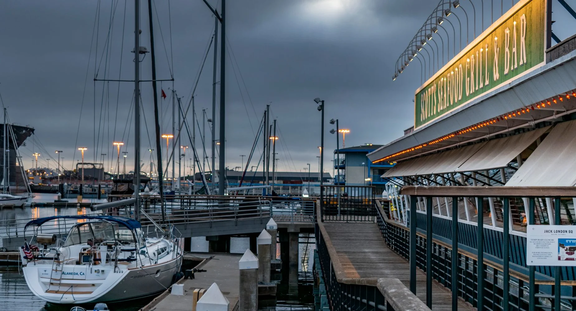 Boats docked at a waterfront marina in the evening