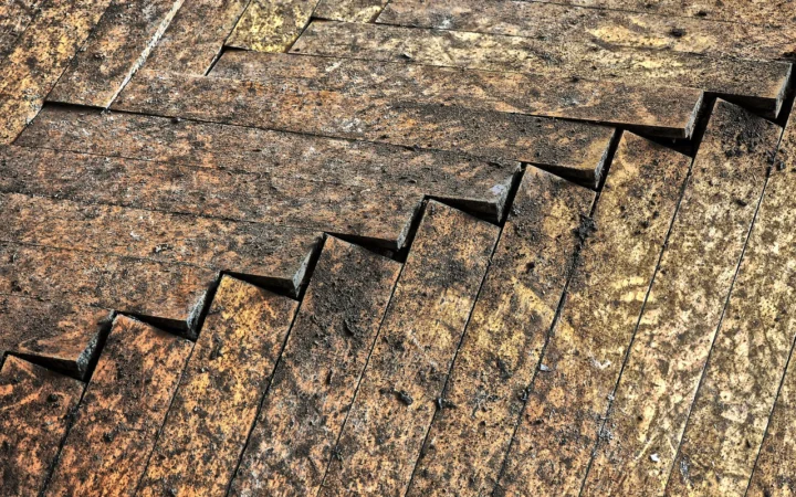 Old herringbone wood floor with swollen, gapped boards from water damage